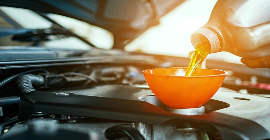 Motor oil being poured into a vehicle engine during a routine oil change service.