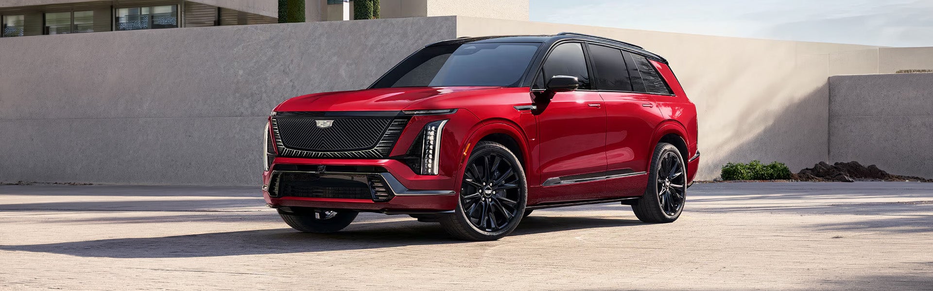 Red Cadillac Escalade SUV parked outside a modern luxury residence.